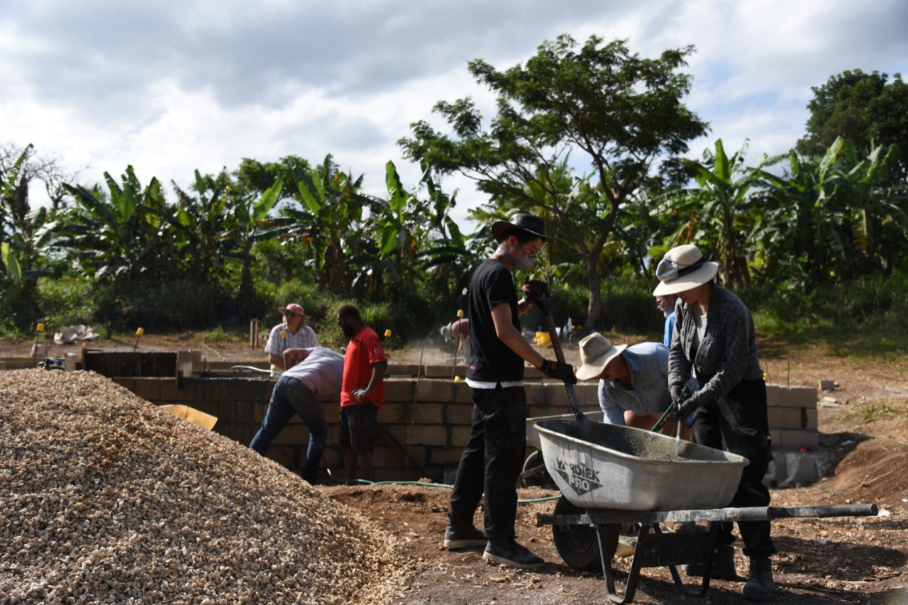 Photograph of students and community members at work on the building site.