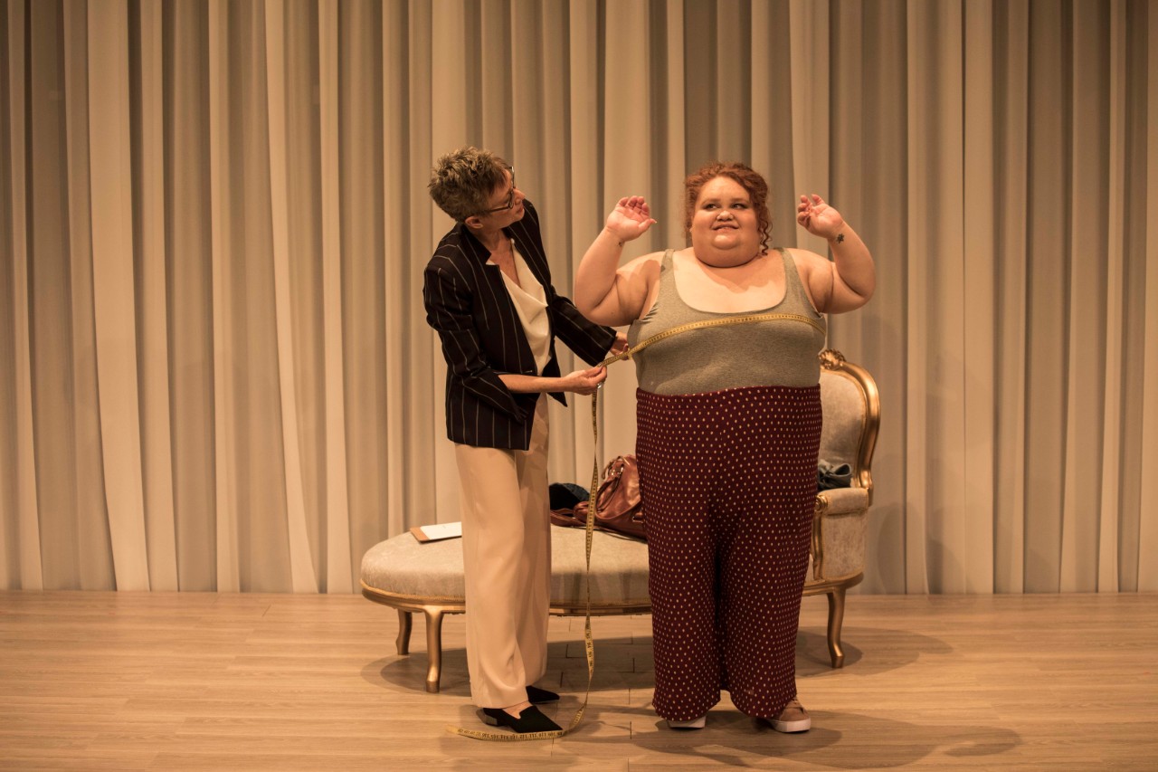 photo of actor Megan Wilding, a larger woman, being measured for a wedding dress