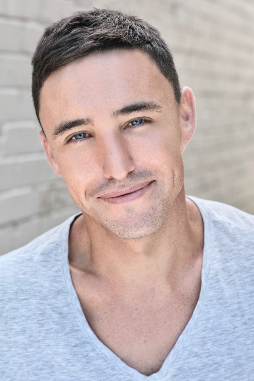 Ben Gerrard is a young man with short brown hair in a grey tshirt smiling at the camera
