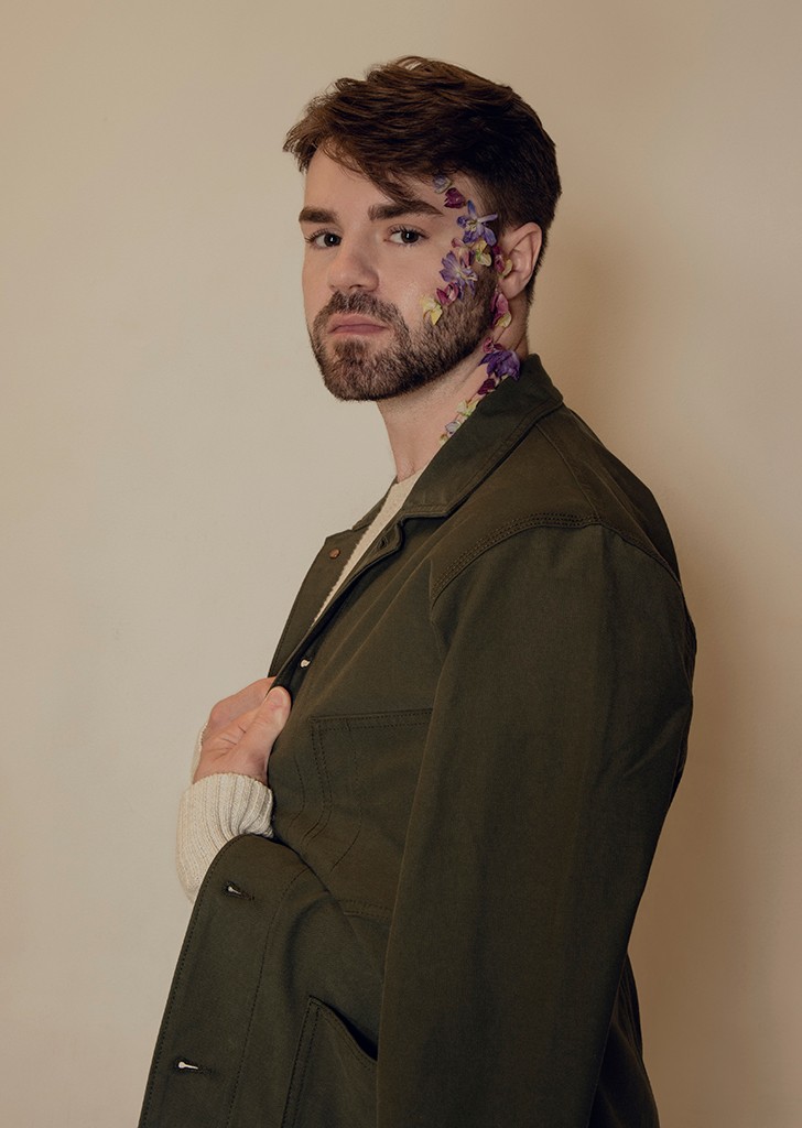 Joseph side on looking at camera, flowers are stuck to the side of his face