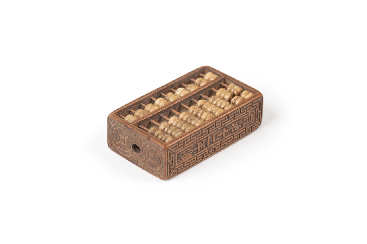 Toggle of a miniature abacus with a hidden compartment. 