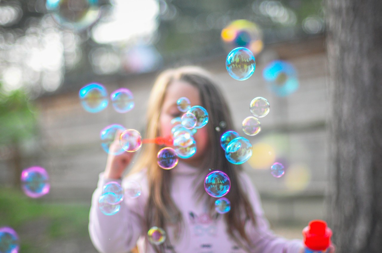young girl blowing bubbles in the garden