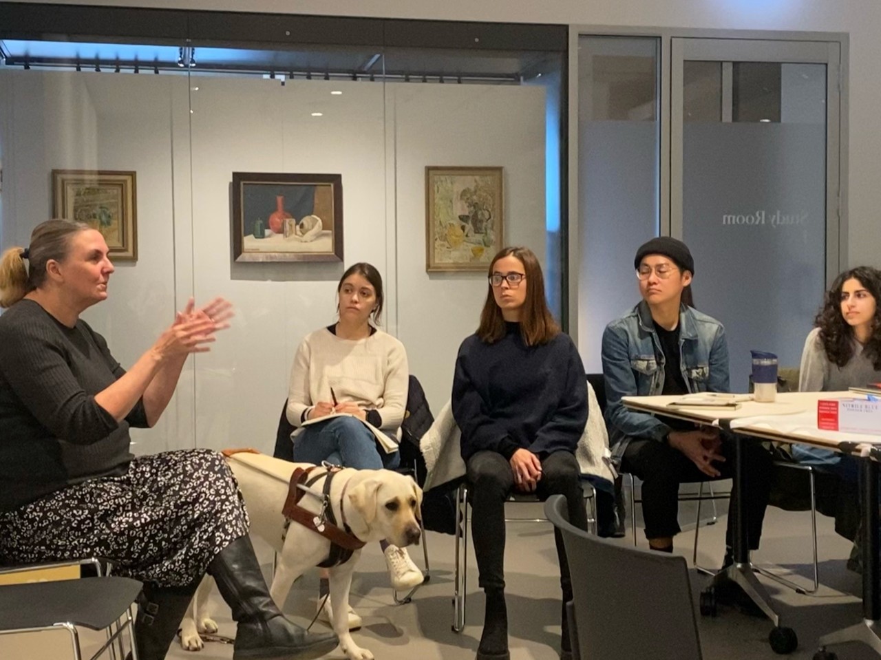 Dr Sheelagh Daniels-Mayes, her guide dog Topaz, some students, sitting in a circle talking with each other