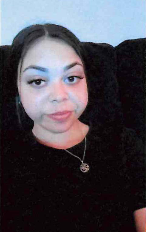 A headshot of Jacinta Elemes. Jacinta has long black hair and is wearing it tied up, and is wearing a black t-shirt. 