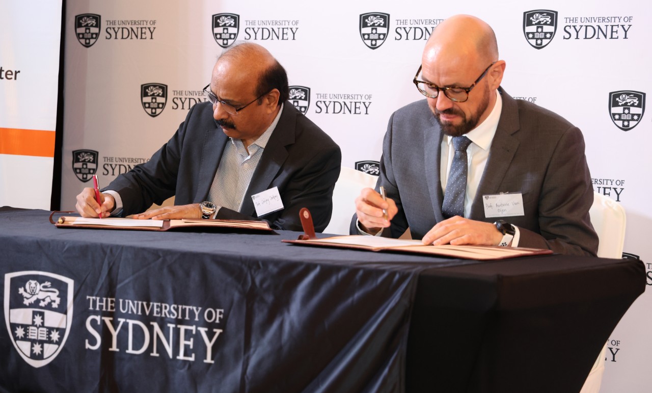 Two people sitting at a table, signing a contract
