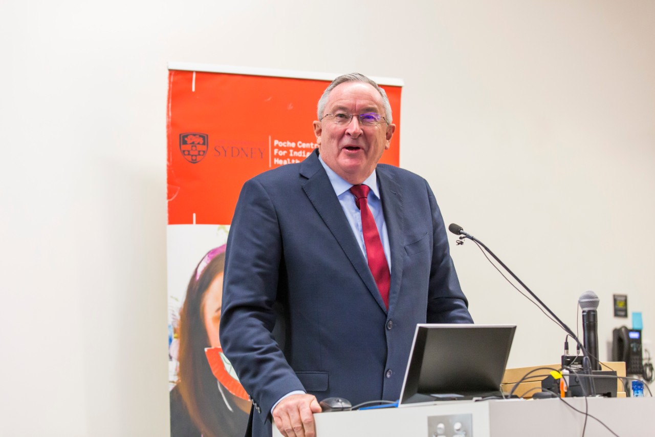 A photo of Minister Hazzard speaking in front of a microphone.