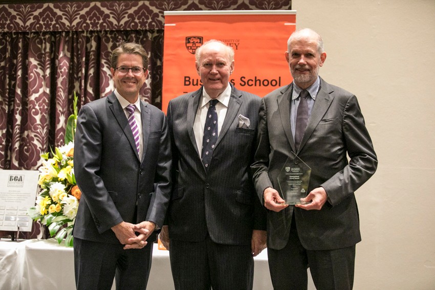 photo of three men standing in a line shaking hands: Kevin Anderson, David Hensher and Neil Smith.