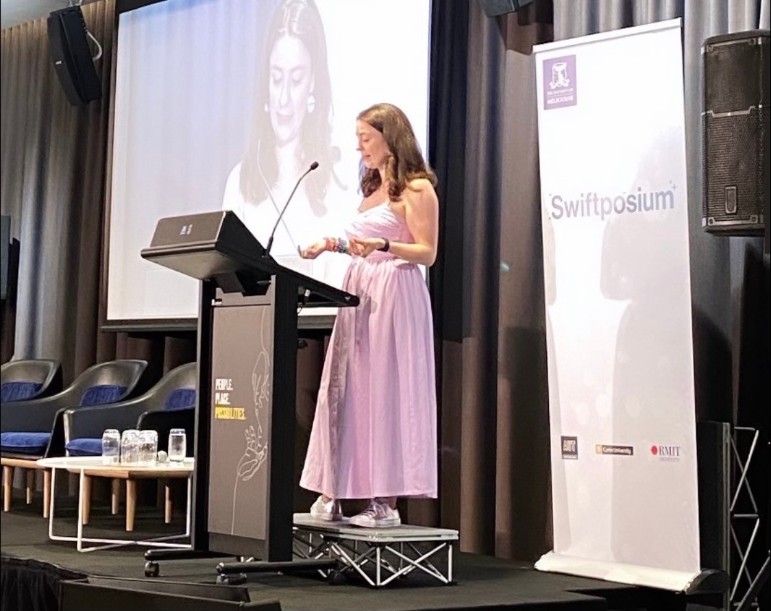 a young woman in a pink dress is giving a talk about Taylor Swift