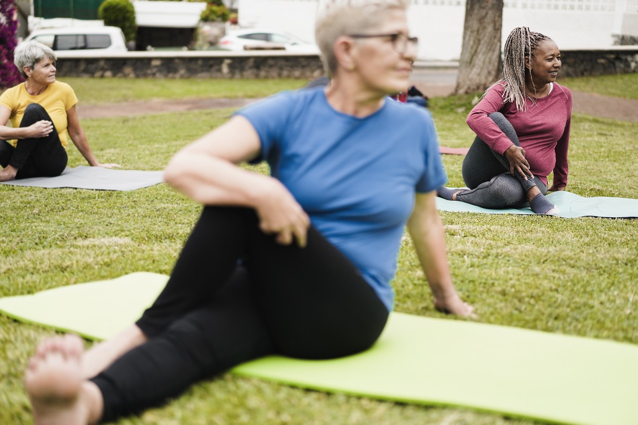 Three women doing yoga stretches in the park