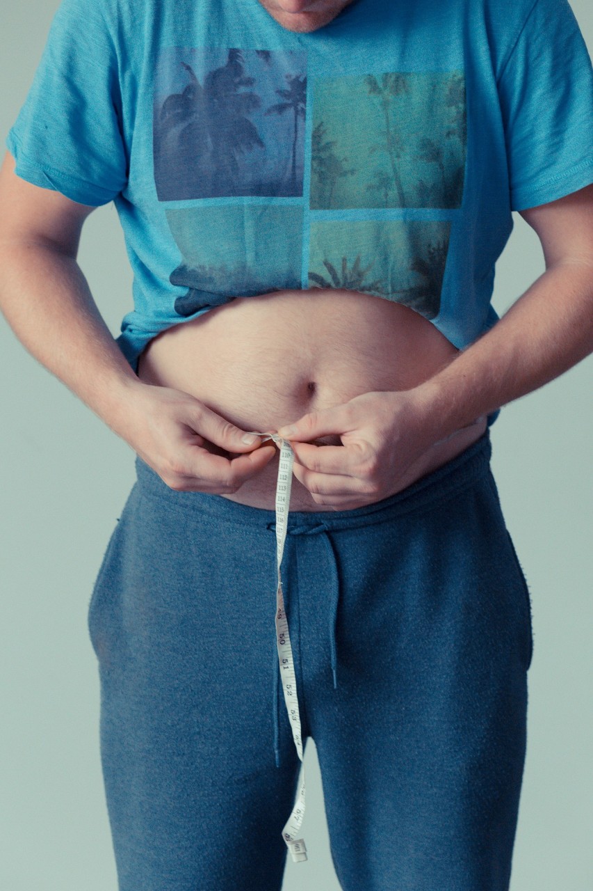 A man measuring his waist with measuring tape. 
