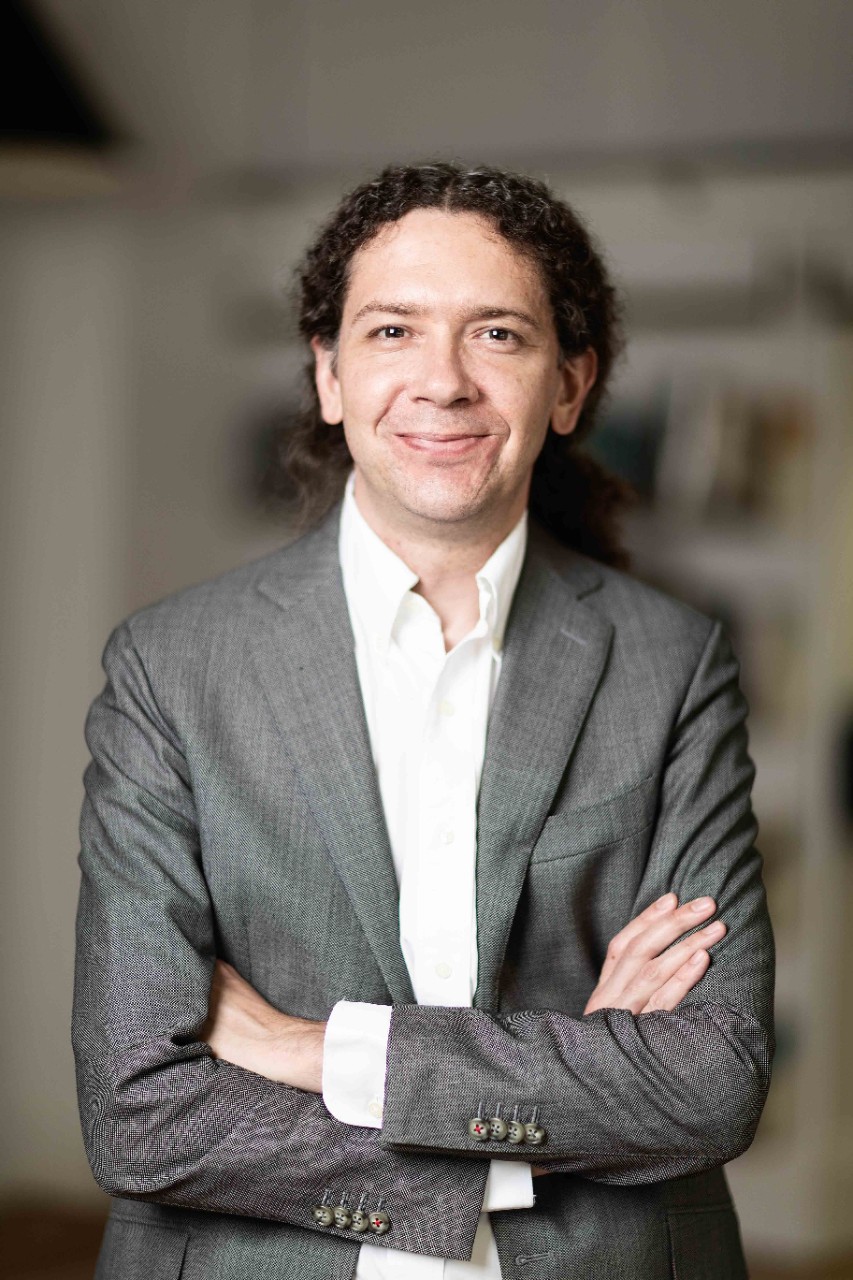man smiles at the camera, his arms are crossed in front