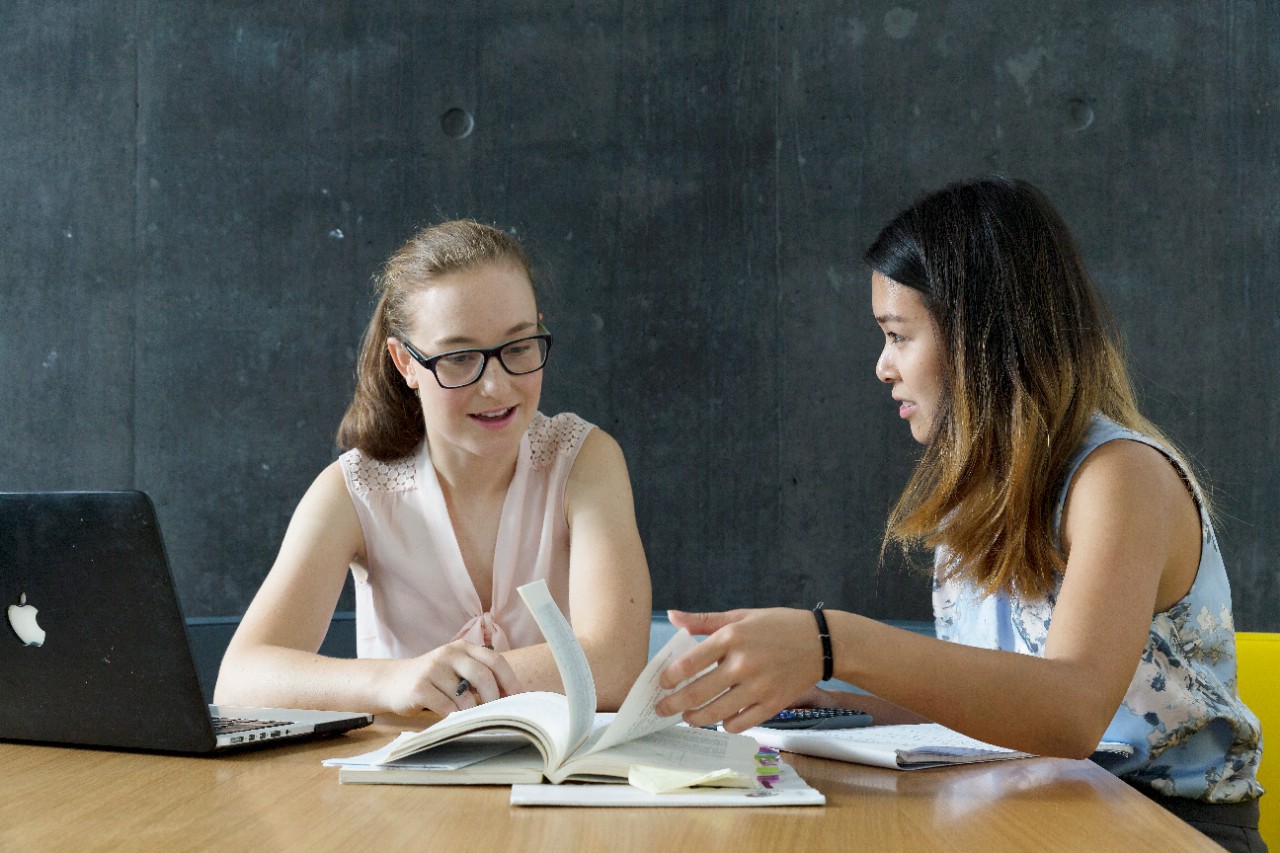 Two female students studying with a calculator and textbook.