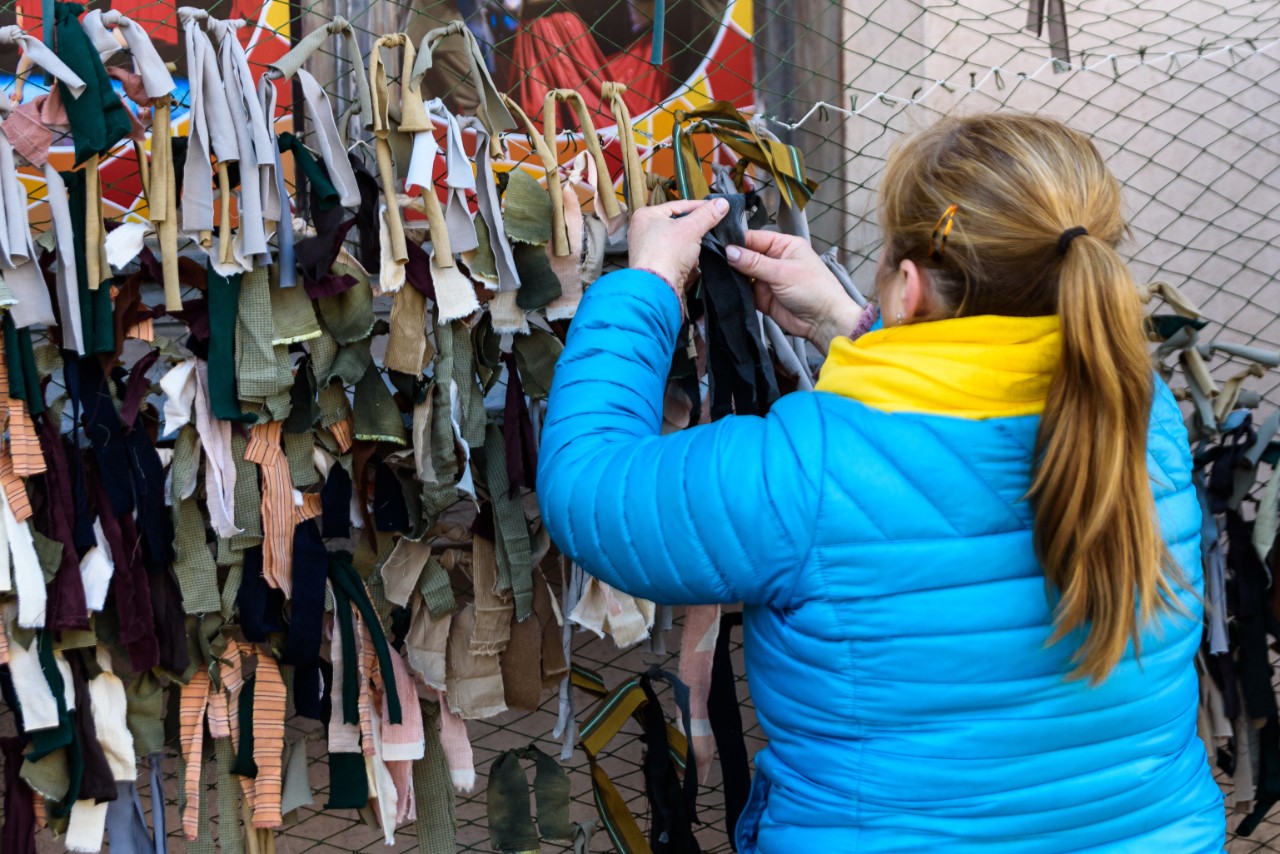 young girl with hair in ponytail pinning cloth to a net to make camouflage netting